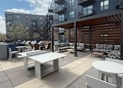 Thumbnail 39 of 45 - A patio with a table and chairs is surrounded by apartment buildings.