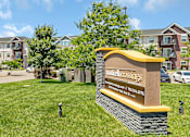 Thumbnail 20 of 24 - a sign in the grass in front of an apartment building