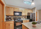 Thumbnail 1 of 11 - an updated kitchen with black appliances and wood cabinets