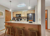 Thumbnail 8 of 11 - a kitchen with wooden cabinets and a counter with three bar stools