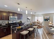 Thumbnail 1 of 9 - Open kitchen and living area with a large window and door to balcony or patio. Kitchen has dark wood cabinetry and large island for entertaining.