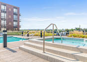 Thumbnail 20 of 40 - a pool and spa with a building in the background
