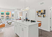 Thumbnail 6 of 40 - a kitchen with white cabinets and a white counter top and a door to a living