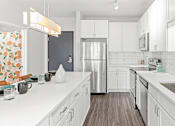 Thumbnail 3 of 40 - a kitchen with white cabinets and a stainless steel refrigerator