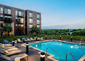 Thumbnail 18 of 40 - Rooftop pool deck looking out onto green St. Paul grounds. Pool is lined by lights and lounge seating.