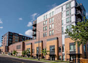 Thumbnail 31 of 40 - Exterior of Oxbo Urban Rentals looking building from the street with shrubbery lining the sidewalk.