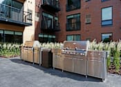 Thumbnail 22 of 40 - Outdoor grilling station with the exterior brick of Oxbo Urban Rentals behind.