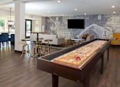 Thumbnail 28 of 40 - Large, bright clubroom complete with entertaining bar, shuffleboard, and TV lounge area with large glass doors looking out into the pool deck.