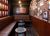 Thumbnail 30 of 40 - Private clubroom styled as a speakeasy with leather booths and brick gallery wall.