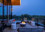 Thumbnail 55 of 58 - a patio with a fire pit and chairs on a balcony