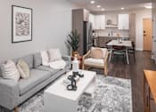 Thumbnail 10 of 58 - a living room with a gray couch and a white coffee table