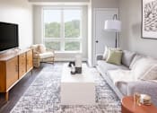 Thumbnail 12 of 58 - a living room with a gray couch and a white coffee table