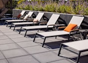 Thumbnail 36 of 58 - a row of chaise lounges with orange pillows are lined up on a patio