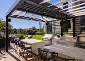 Thumbnail 40 of 58 - a pergola with white tables and chairs on a patio with a grill and a television