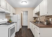 Thumbnail 7 of 34 - A kitchen with white appliances and cabinets.