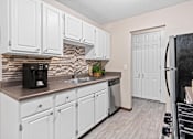 Thumbnail 10 of 34 - A kitchen with white cabinets and a black refrigerator.