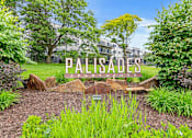 Thumbnail 25 of 34 - A garden with a sign that says Palisades Apartments.