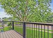 Thumbnail 11 of 34 - A tree is in the background of a balcony.