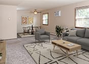 Thumbnail 8 of 34 - A living room with a grey couch, a coffee table, and a rug.