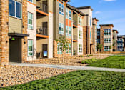 Thumbnail 39 of 42 - Parkhouse courtyard with green grass, rock beds and concrete walking path