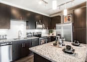 Thumbnail 7 of 42 - Kitchen with center island, dark wood cabinets, granite countertops and stainless steel appliances