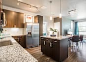 Thumbnail 6 of 42 - Kitchen open to living room, with dark wood cabinets and granite countertops, central island with overhead lighting