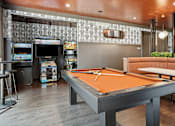 Thumbnail 33 of 42 - A pool table is in the middle of a room with a bar and arcade games.