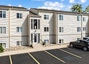 Thumbnail 11 of 11 - an apartment building with white siding and a parking lot