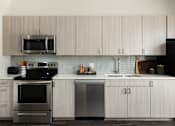 Thumbnail 1 of 40 - A modern kitchen with a stove, dishwasher, and microwave.