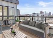 Thumbnail 10 of 40 - a balcony with a couch and a chair and a view of the city
