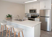 Thumbnail 8 of 28 - Studio unit with a modern kitchen featuring a breakfast bar and white cabinetry.
