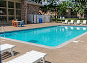 Thumbnail 16 of 23 - a swimming pool with chaise lounge chairs and trees in the background