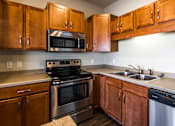 Thumbnail 2 of 18 - an empty kitchen with wooden cabinets and stainless steel appliances