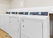 Thumbnail 11 of 14 - a row of washers and dryers in a laundry room