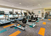 Thumbnail 23 of 29 - A gym with treadmills, elliptical machines, and other exercise equipment.