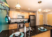 Thumbnail 1 of 12 - Bright and spacious kitchen with stainless steel appliances, pendant lighting above the island, and pan rack on the left side to hang pots and pans.