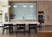 Thumbnail 9 of 34 - A modern kitchen with a glass backsplash and wooden cabinets.