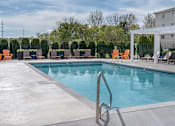 Thumbnail 23 of 34 - A pool with a metal ladder and chairs around it.
