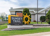 Thumbnail 34 of 34 - A sign for Sunset Trail Apartment Homes is displayed in front of a building.