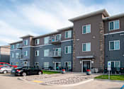 Thumbnail 15 of 15 - Exterior The Gardens Apartments Entrance and Parking Lot