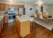 Thumbnail 5 of 12 - Bright and spacious kitchen with stainless steel appliances, large island, and separate dining area.