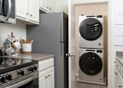 Thumbnail 1 of 28 - A modern kitchen with a stove, microwave, and a washing machine at The Bosk Apartment Homes, Woodbury, MN