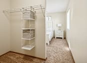 Thumbnail 10 of 29 - A white bedroom with a bed, nightstand, and a closet with shelves.