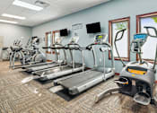Thumbnail 13 of 29 - A gym with treadmills, elliptical machines, and other exercise equipment.