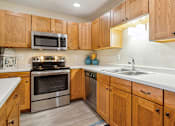 Thumbnail 2 of 29 - A kitchen with wooden cabinets and stainless steel appliances.