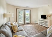 Thumbnail 4 of 29 - A living room with a grey couch and a white entertainment center.