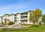 Thumbnail 25 of 29 - The Legacy apartment complex is surrounded by a grassy area and trees.
