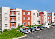 Thumbnail 1 of 9 - an exterior view of an apartment building with cars parked in a parking lot
