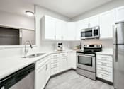 Thumbnail 9 of 33 - Modern and spacious kitchen with white cabinetry, stainless steel appliances, and plenty of storage.