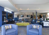Thumbnail 13 of 29 - a lobby with blue couches and chairs with a yellow couch in the middle of the room